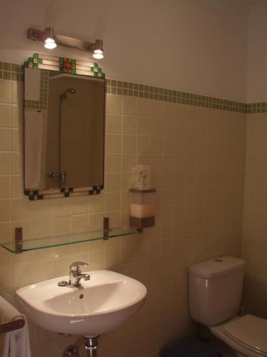a bathroom with a sink and a toilet and a mirror at Hostal de la Luz in Cuenca
