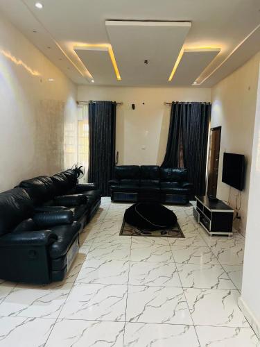 a living room with black leather couches and a television at Exotic 3 bedroom flat in Aco, Lugbe in Abuja
