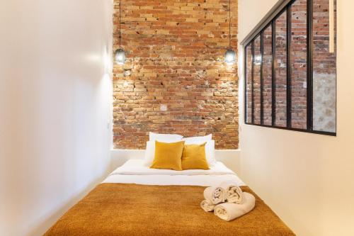 - une chambre avec un mur en briques et un lit avec des serviettes dans l'établissement Cozy Apartment in heart of Montmartre, à Paris