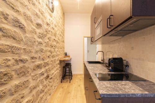 une cuisine avec un mur en pierre et un comptoir dans l'établissement Cozy Apartment in heart of Montmartre, à Paris