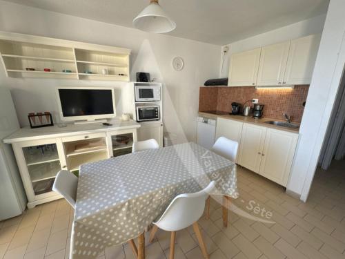 une cuisine avec une table et des chaises et une cuisine avec des armoires blanches dans l'établissement 40 M², 1ERE LIGNE MER, DERNIER ETAGE AVEC ASCENSEUR, à Sète