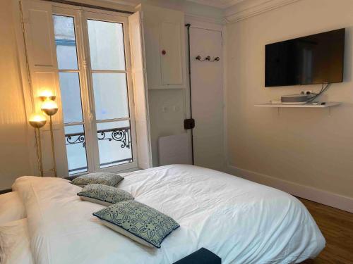 a bedroom with a white bed with two pillows on it at Superbe appartement quartier latin in Paris