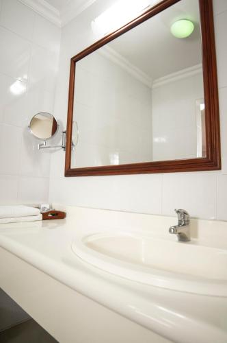 a white bathroom with a sink and a mirror at Gran Hotel De Lago - El Coca in Puerto Francisco de Orellana