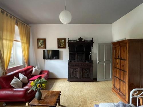 a living room with a red couch and a table at Ferienwohnungen Jowatzky Altkötzschenbroda in Radebeul