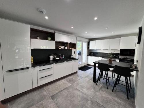 une cuisine avec des armoires blanches et une table à l'intérieur dans l'établissement Le Logis des Fées, à Gérardmer