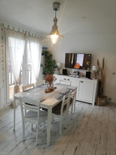 une salle à manger avec une table et des chaises et une télévision dans l'établissement Brise Marine, à Merville-Franceville-Plage