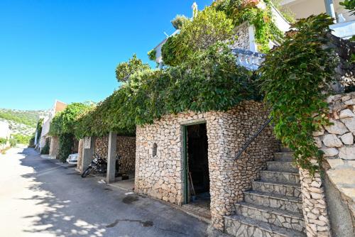 a stone building with stairs and ivy on it at Apartments Marić in Primošten