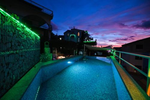 a swimming pool with lights on the side of a building at Apartments Marić in Primošten