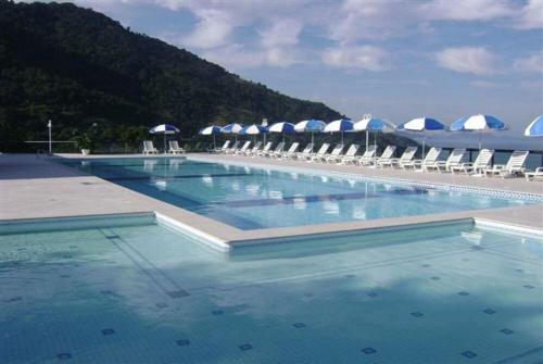 a large swimming pool with chairs and umbrellas at Porto Real Resort - Apto 3 Suites - Por do Sol Genial in Mangaratiba