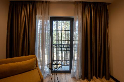 a living room with a couch and a large window at PineHill Hotel, Restaurant , Pool & Spa - RAZEM in Razëm