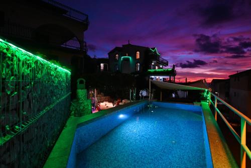 a swimming pool with green lights on a building at night at Apartments Marić in Primošten