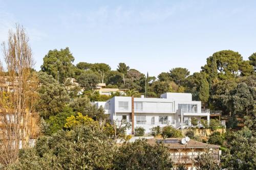 une maison blanche sur une colline avec des arbres dans l'établissement Studio Bougainvillier - Welkeys, à Cavalaire-sur-Mer