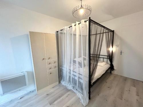 - une chambre avec un lit bébé noir et des rideaux dans l'établissement Appart T2 magnifique vu océan, à Saint-Hilaire-de-Riez