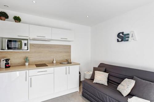 un salon avec un canapé et une cuisine dans l'établissement Appartement Dattier - Welkeys, à Cavalaire-sur-Mer