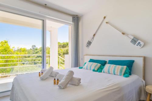 - une chambre blanche avec une grande fenêtre et un lit dans l'établissement Appartement Figuier - Welkeys, à Cavalaire-sur-Mer