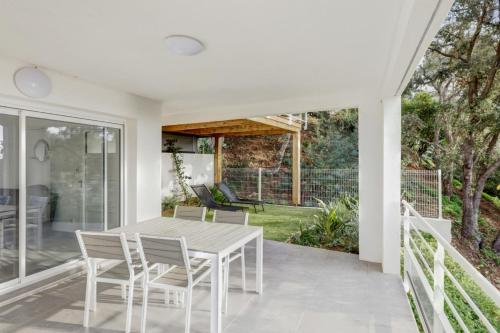 une salle à manger blanche avec une table et des chaises sur une terrasse dans l'établissement Appartement Figuier - Welkeys, à Cavalaire-sur-Mer