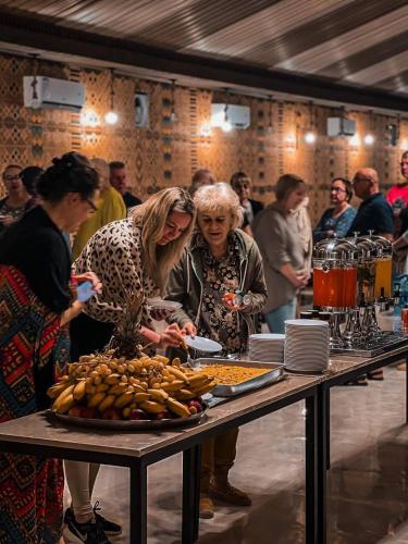 a group of people standing around a table with food at Charlotte luxury camp in Wadi Rum