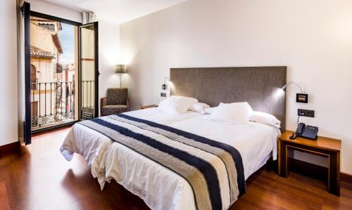 Habitación de hotel con cama grande y ventana en Monjas del Carmen Hotel, en Granada