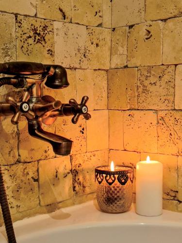 a bathroom sink with a candle and a faucet at Saints & Sinners Romantic Jacuzzi in Bucharest