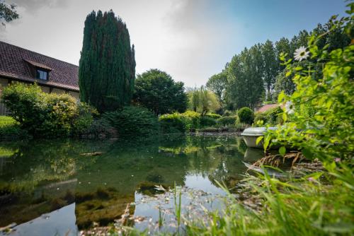 un étang dans une cour avec une maison et des arbres dans l'établissement La Ferme des Templiers de Fléchinelle, à Enquin-les-Mines