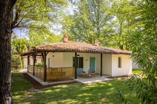 a small white house with a porch in a yard at Club del Sole Tenuta Primero Grado Family Collection in Grado