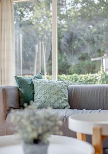 a couch with two pillows in front of a window at Bungalowpark Het Verscholen Dorp in Harderwijk