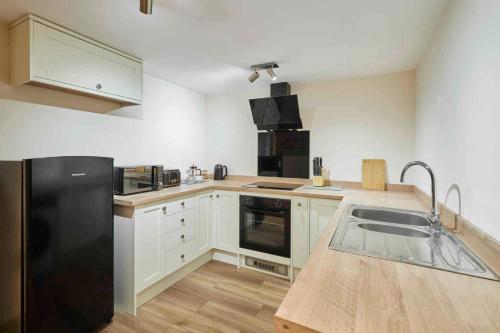 a kitchen with a black refrigerator and a sink at Host & Stay - St Mary's Riverside in Whitby