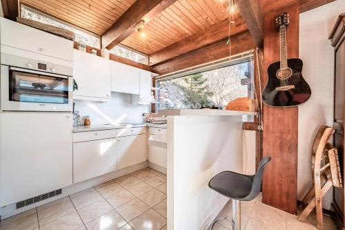 a kitchen with white cabinets and a guitar on the wall at Chalet Châtel - calme et spacieux in Châtel