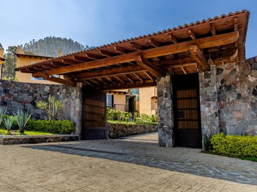 an entrance to a stone building with a wooden pergola at Hotel Campestre, Valle de Bravo in Valle de Bravo