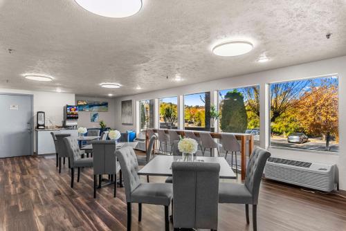 a dining room with tables and chairs and windows at Clarion Pointe Wenatchee in Wenatchee