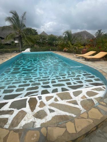 a large swimming pool with a pattern in the water at Red Sunshine Villa B&B in Malindi