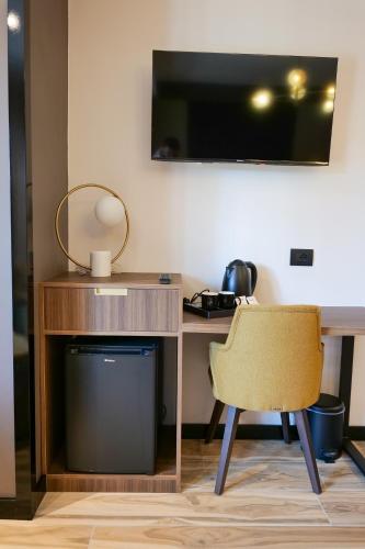 a desk with a chair and a television on a wall at PineHill Hotel, Restaurant , Pool & Spa - RAZEM in Razëm