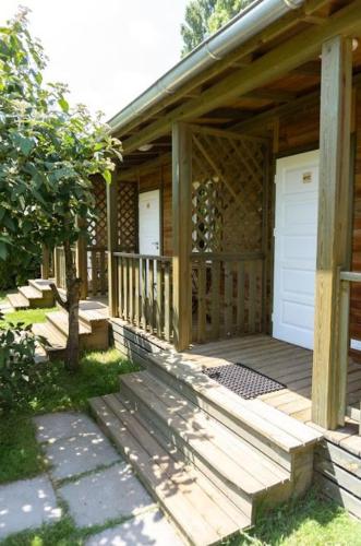 a porch of a wooden cabin with a white door at Domaine des Epinettes in Saint-Romain-de-Jalionas