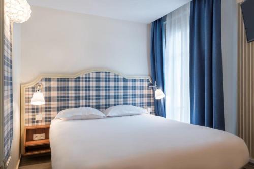 a bedroom with a white bed with blue curtains at Hotel Boris V. by Happyculture in Levallois-Perret
