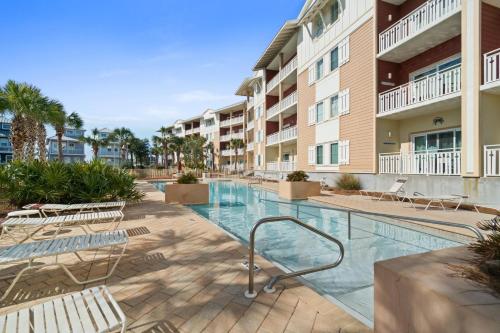 a swimming pool at a apartment complex with chairs and a building at Waterside Village by Panhandle Getaways in Mexico Beach