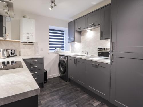 a kitchen with gray cabinets and a sink and a dishwasher at 3 The Granary in Banff