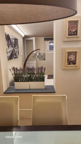 a mirror in a room with some flowers on a counter at appartamento comfort Malpensa check in h 24 posto auto privato in Casorate Sempione
