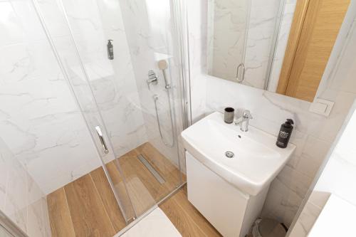 a white bathroom with a sink and a shower at Royal Premium by Vucko Jahorina Serviced Apartments in Jahorina