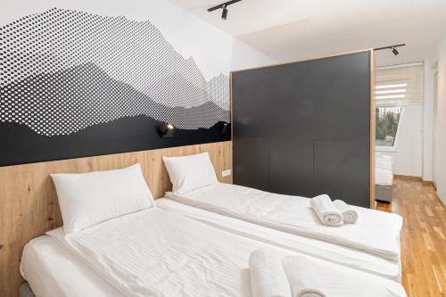 two beds in a bedroom with a black and white wall at Royal Premium by Vucko Jahorina Serviced Apartments in Jahorina