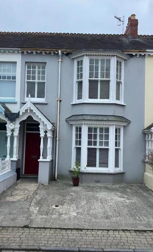 a white house with a red door at Tenby Victorian Villa with parking, pets allowed in Pembrokeshire