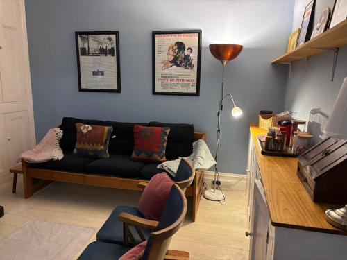 a living room with a black couch and a table at Tenby Victorian Villa with parking, pets allowed in Pembrokeshire