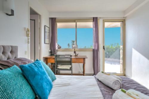 - une chambre avec un lit doté d'oreillers bleus et d'un bureau dans l'établissement Bas de Villa VUE PANORAMIQUE, à Vallauris
