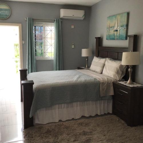 una camera da letto con un letto, due lampade e una finestra di Hills Royale Villa -Ironshore Montego Bay a Montego Bay