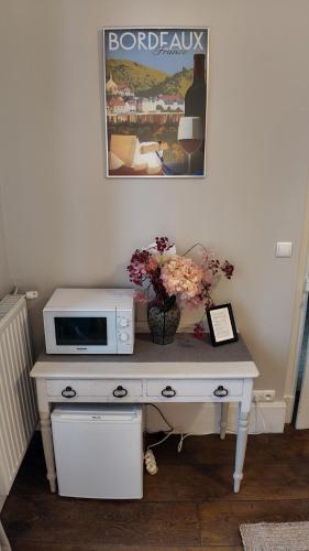 a white desk with a microwave and flowers on it at Repos à Ribérac B&B in Ribérac