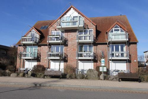 a large brick building with benches in front of it at Strandduene Stranddüne Appartement 12 in Haffkrug
