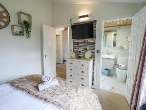 a bedroom with a bed and a television on a wall at Our Happy Place in Carnforth
