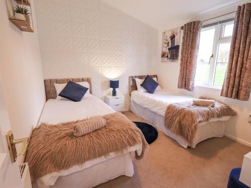a bedroom with two beds with blankets and a window at Our Happy Place in Carnforth