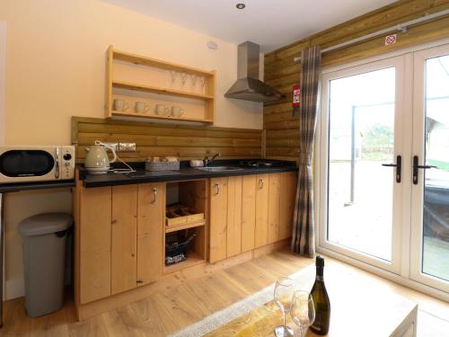 a kitchen with wooden cabinets and a sink and a window at Robin's Nest Lodge in Snettisham