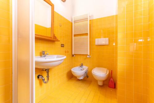 a yellow bathroom with a sink and a toilet at Villa Eden in Falcade