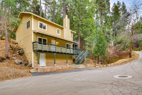 a yellow house with a balcony in the woods at 4 Mi to Lake Arrowhead Cabin with Grill and Deck! in Twin Peaks